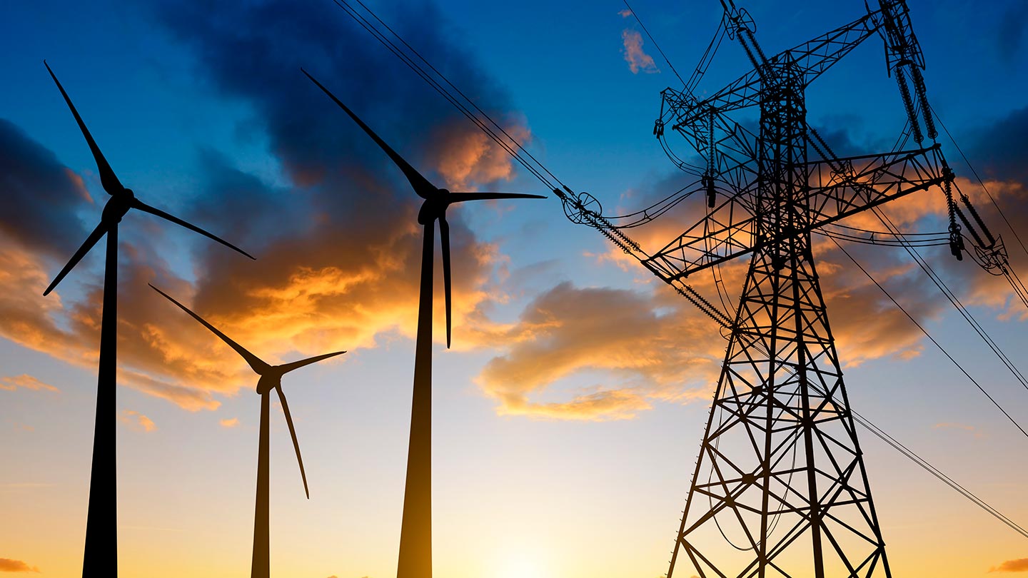 Electricity pylon, wind turbines and nuclear power station at sunset